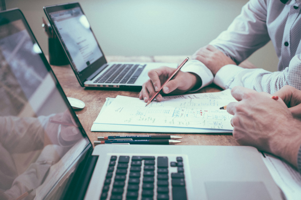 Two professionals collaborating over laptops and paperwork to implement a strategic partner relationship management plan.